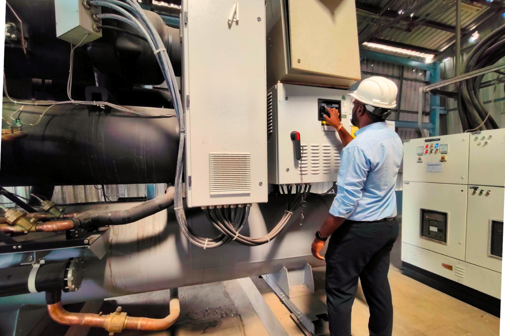 Industrial engineer operating an HVAC chiller system in a manufacturing facility for energy efficiency and cooling system maintenance.